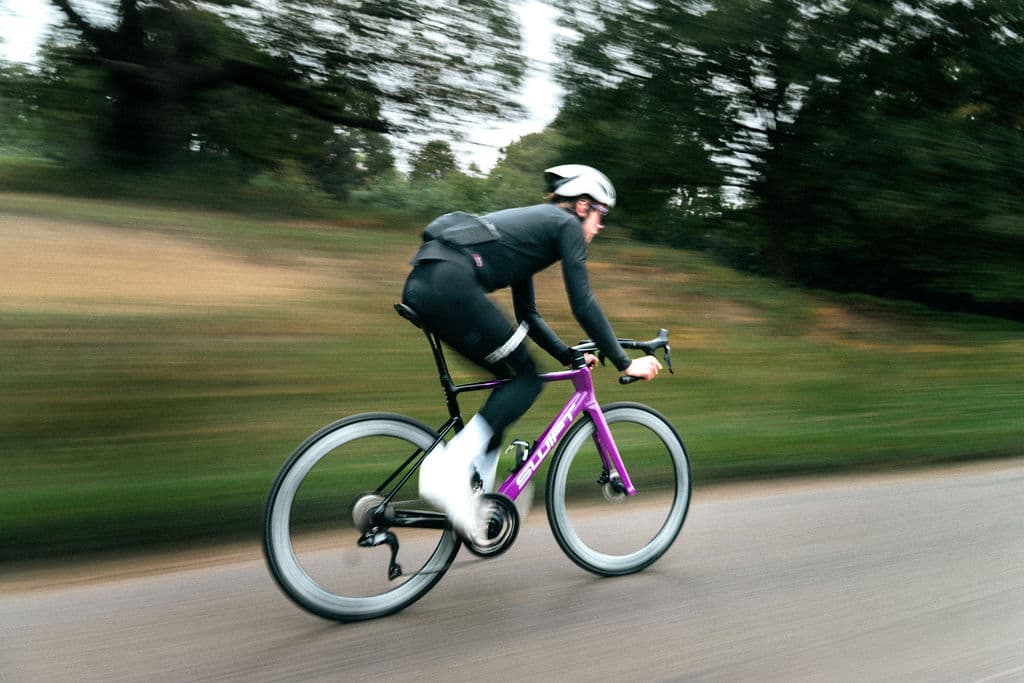 Ciclista em velocidade com bike SWIFT roxa, motion blur no parque